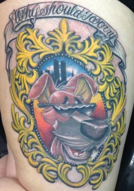 Tattoo of a cartoon dog with sunglasses inside a gold frame.