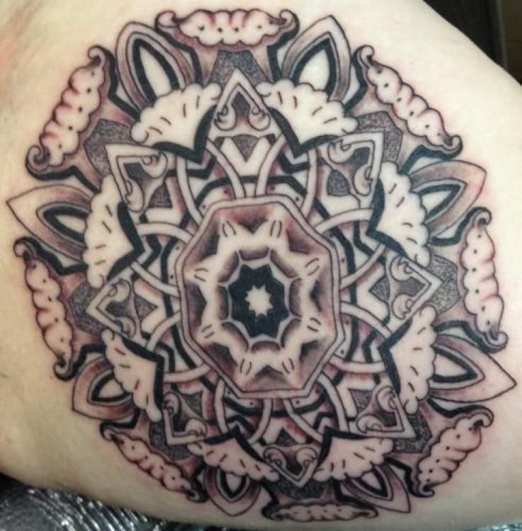 Black and white mandala tattoo with intricate geometric patterns on skin.