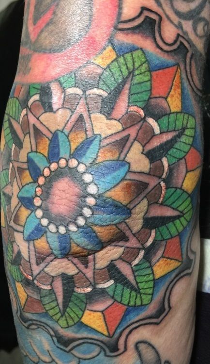 Colorful geometric mandala tattoo on skin.