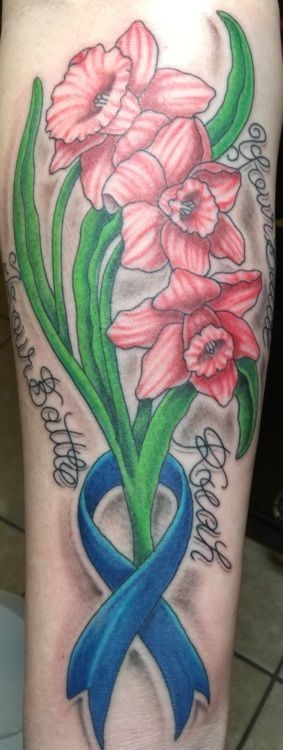Tattoo of three pink daffodils with green stems and leaves, a blue ribbon, and three names.