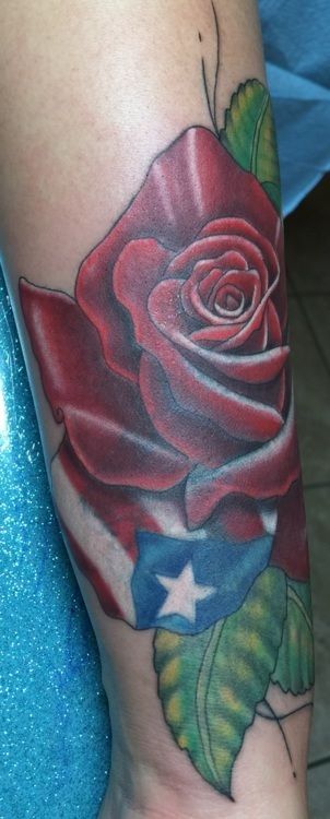 Tattoo of a red rose with a Puerto Rican flag incorporated into the design on an arm.