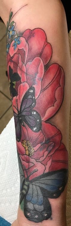 Tattoo of red flowers and dark butterflies on an arm.
