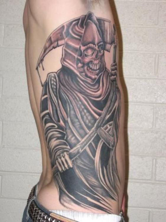 Grim Reaper tattoo on side, holding a scythe. Dark robe, skull face, and brick background.