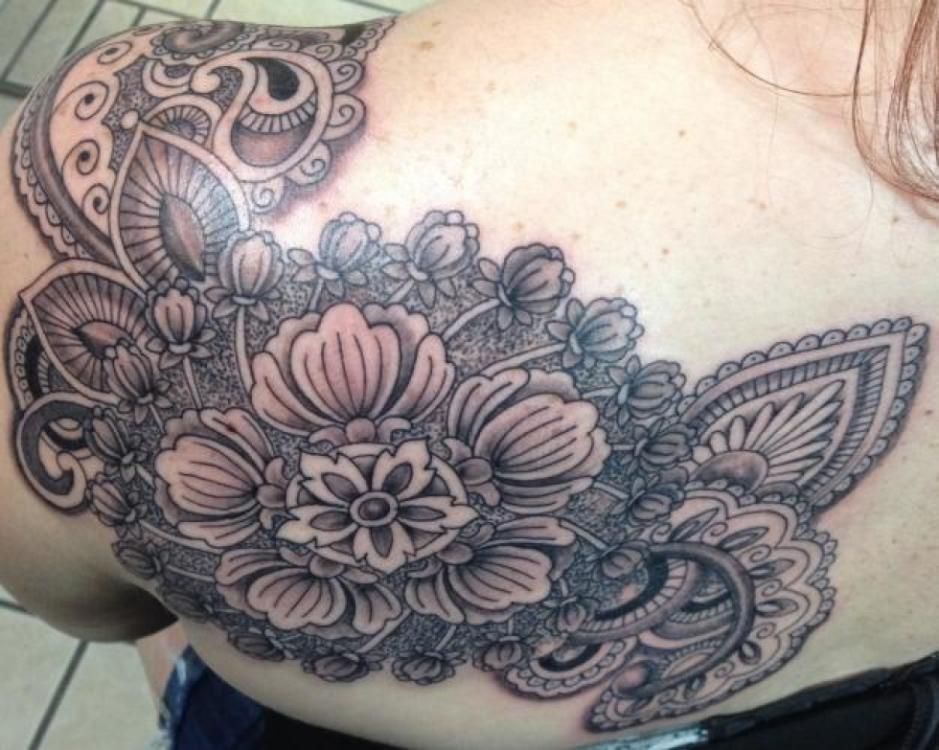 Black ink floral tattoo on a shoulder blade, with detailed patterns and shading.