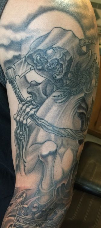 Tattoo on an arm depicting the grim reaper holding a scythe, riding a skeletal horse in front of a moon.
