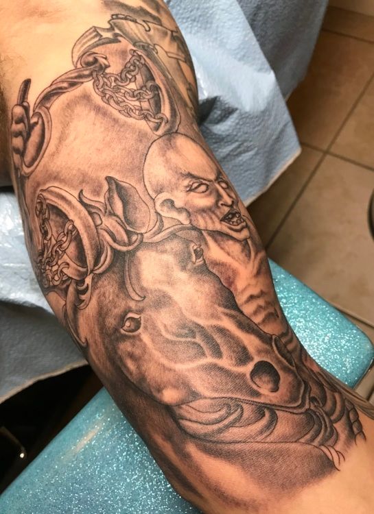 Black and gray tattoo on arm depicting a horse head with a rider and two additional heads above.