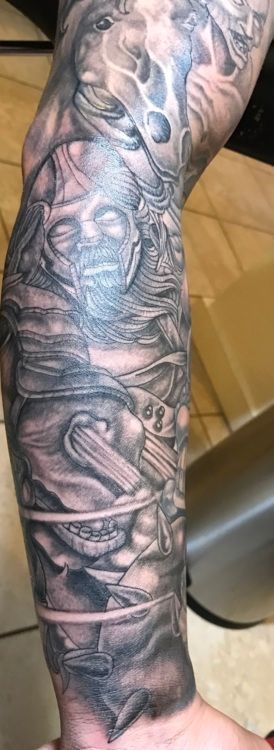 Detailed black and gray arm sleeve tattoo, depicting a surreal, multi-figure scene with intricate shading and detail.