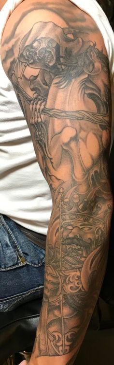 Tattoo of a detailed, dark gray fantasy-themed design covering a person's arm.