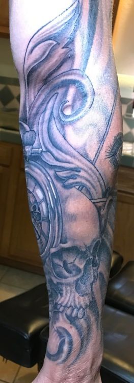 Leg with a detailed black and grey tattoo of swirling designs, possibly a skull and clock.