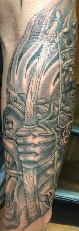 Tattoo of a samurai warrior holding a sword, in black and grey ink on an arm.