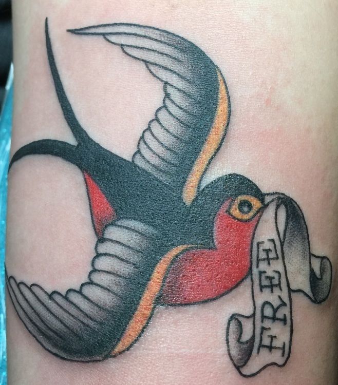 Traditional tattoo of a swallow carrying a scroll that reads 