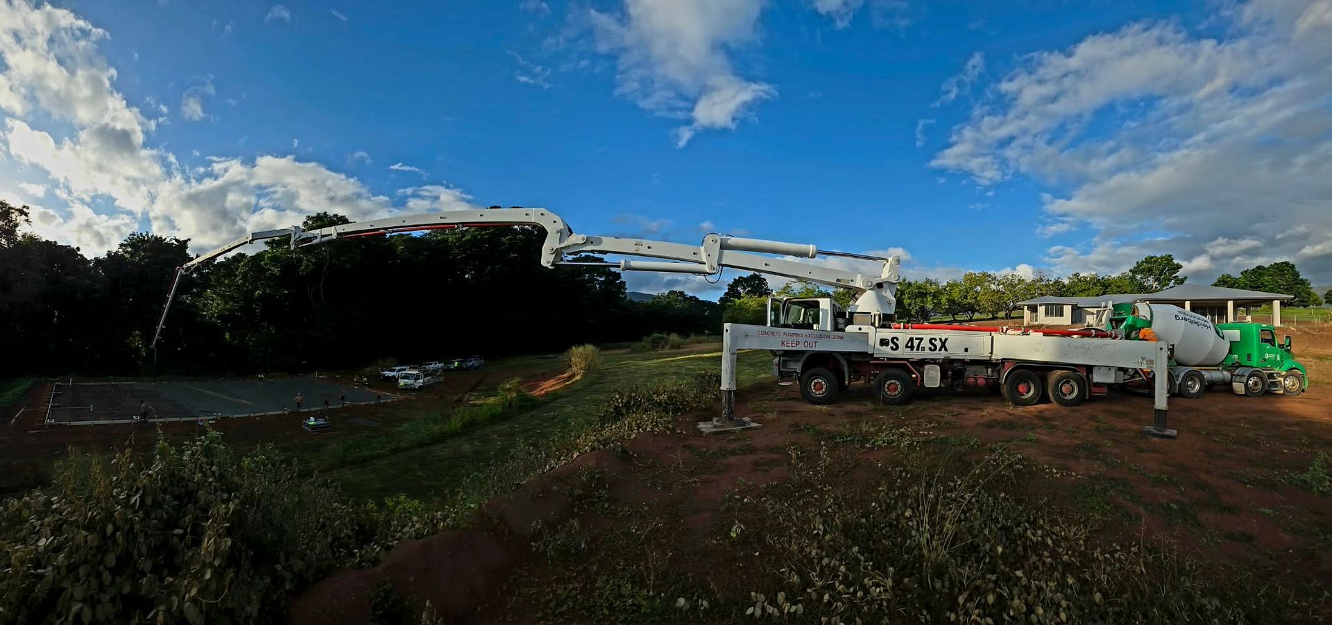Construction site with trucks and machinery on a dirt lot under a blue sky