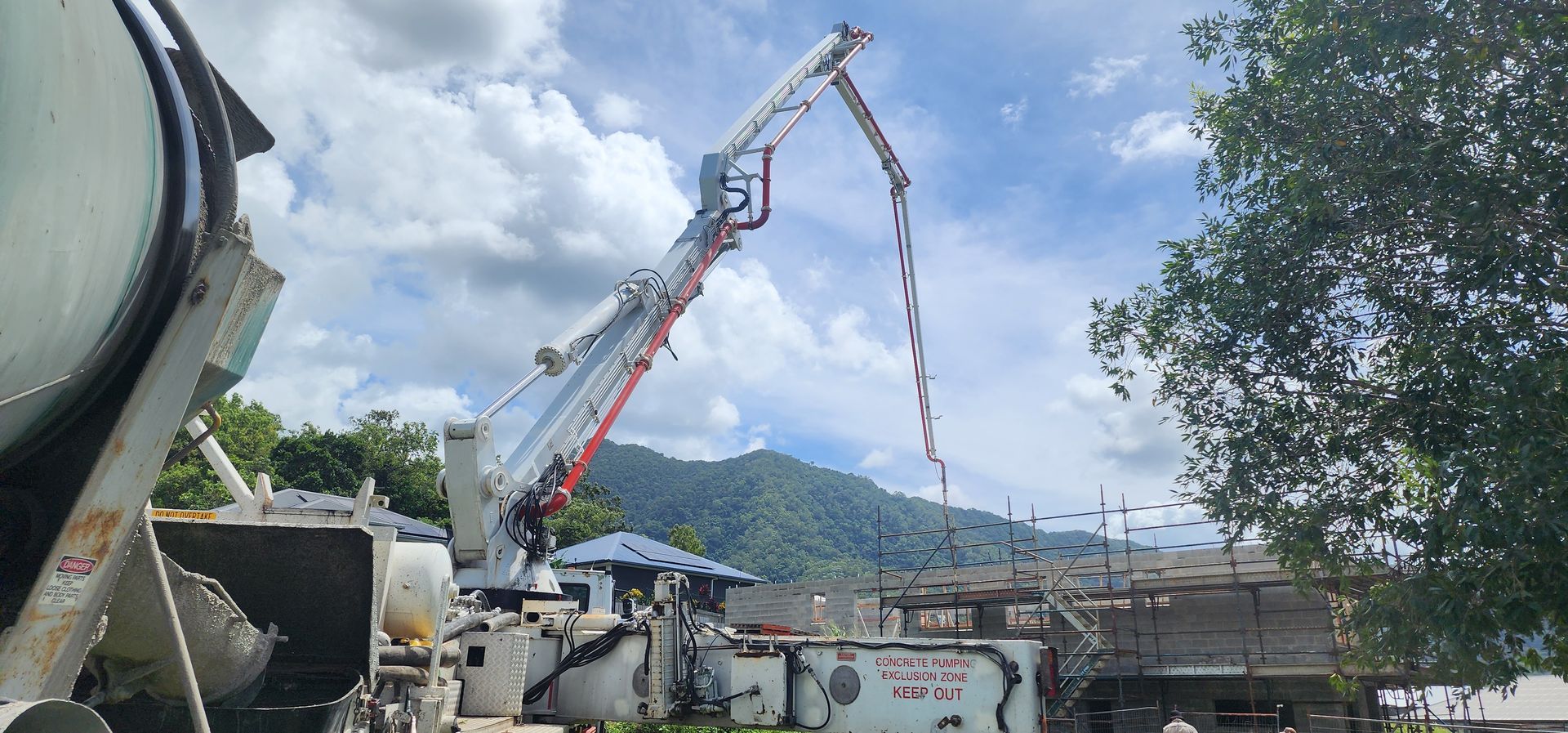 Concrete pump truck pouring concrete at a construction site with mountains in the background