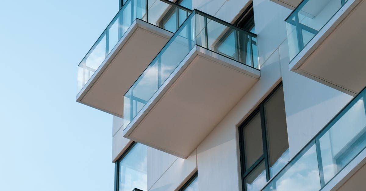 A white apartment building with balconies and windows against a blue sky.
