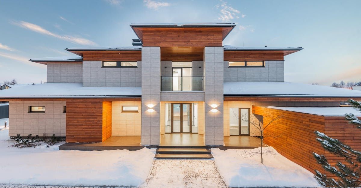 A large house with a lot of windows is covered in snow.