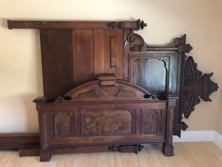 A wooden bed frame is sitting on a wooden floor in a room.