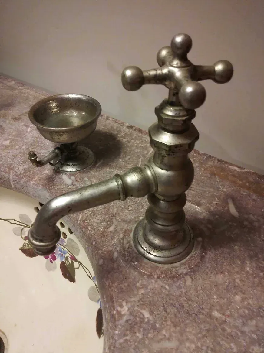A bathroom sink with a faucet and soap dish on the counter.