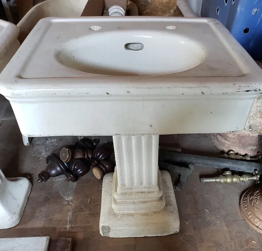 A white pedestal sink with a hole in the middle