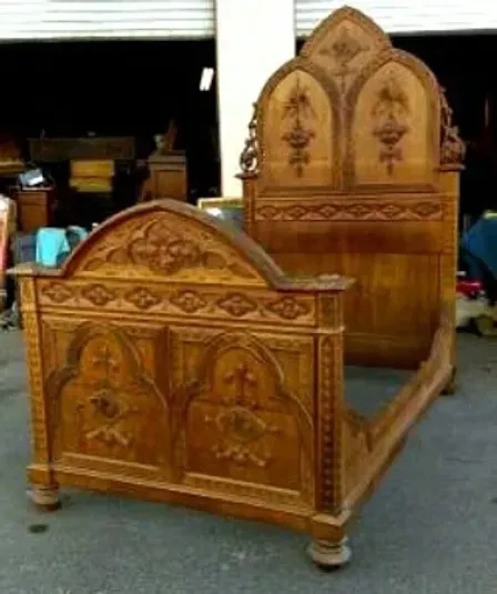 A wooden bed with a carved headboard is sitting in front of a garage door