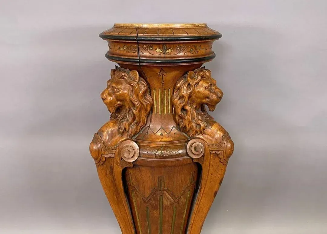 A wooden vase with two lions carved into it is sitting on a table.
