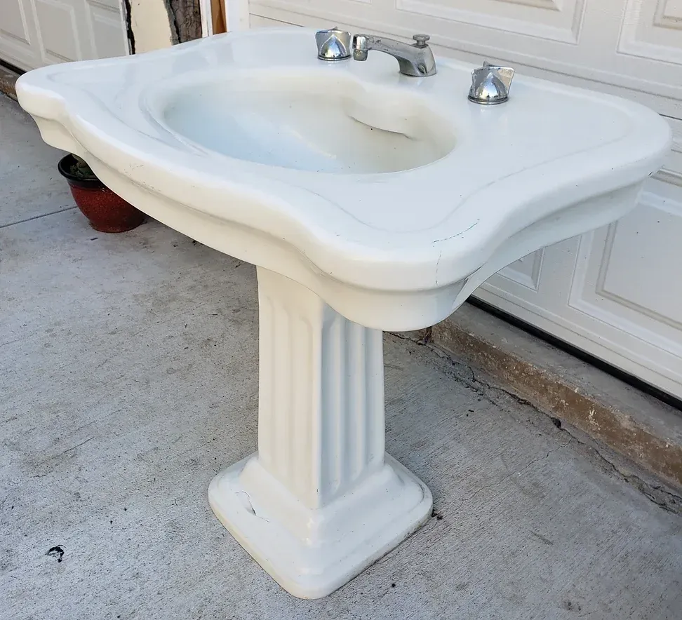 A white pedestal sink with a faucet on it
