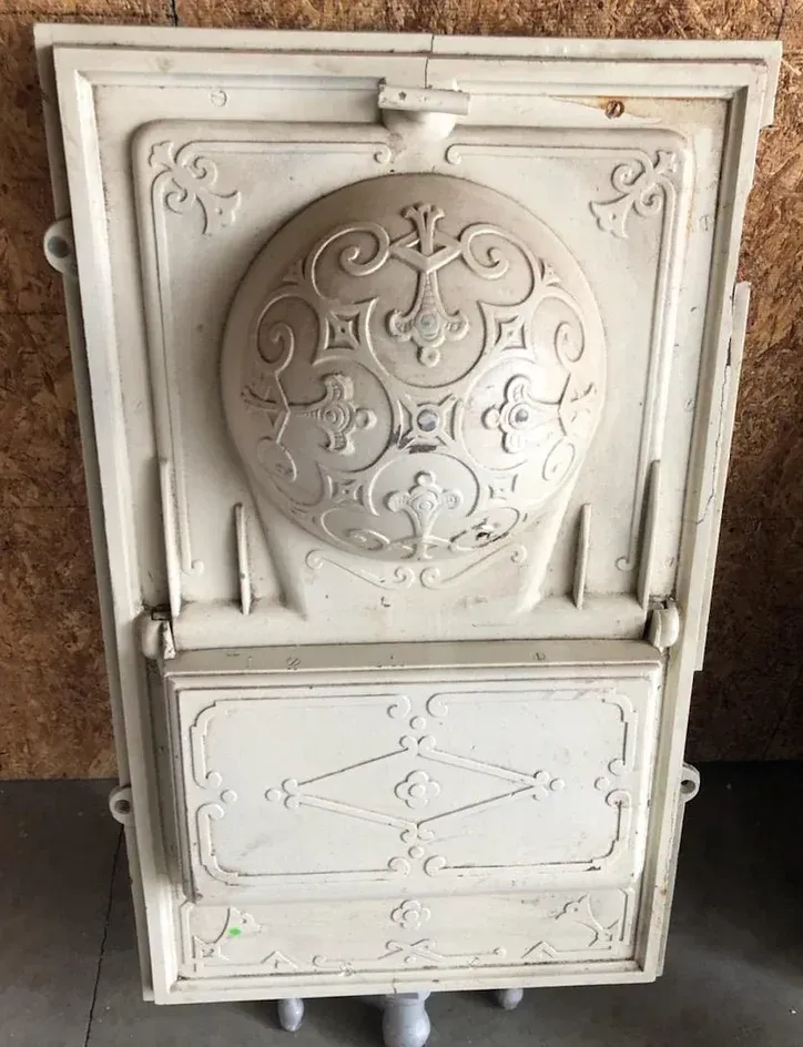 A white door with a circular design on it is sitting on a wooden floor.