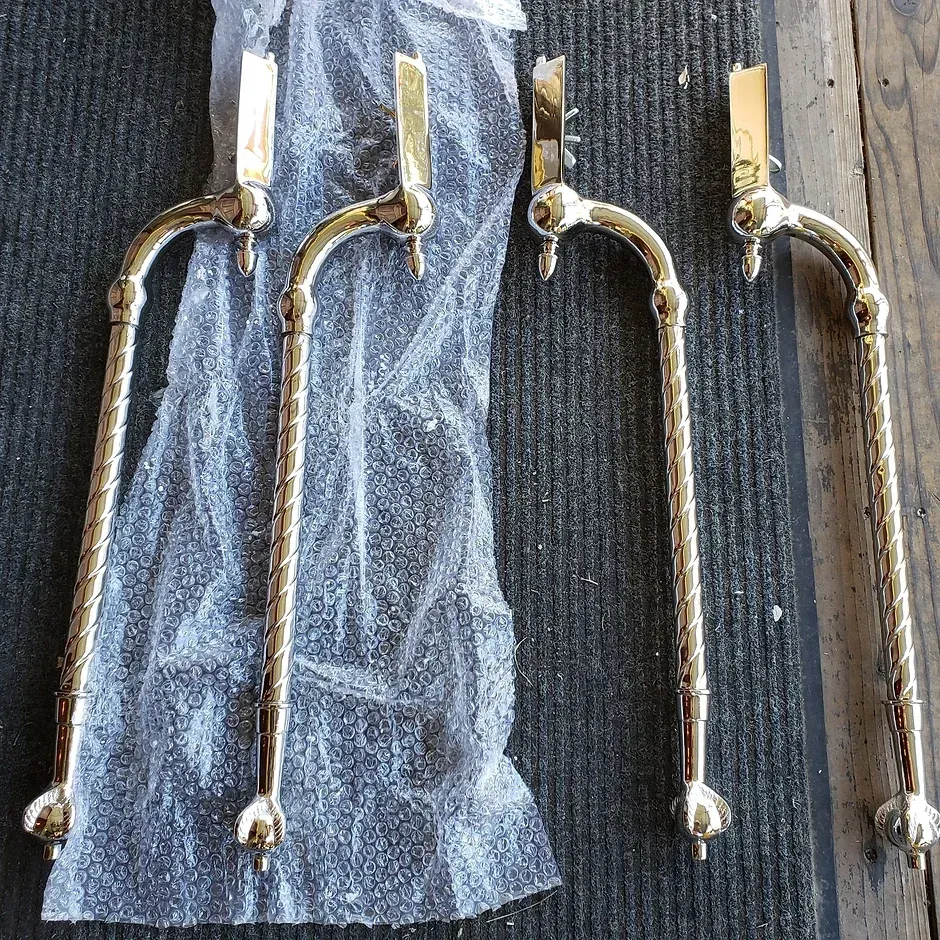 Three brass handles are wrapped in plastic and sitting on a mat