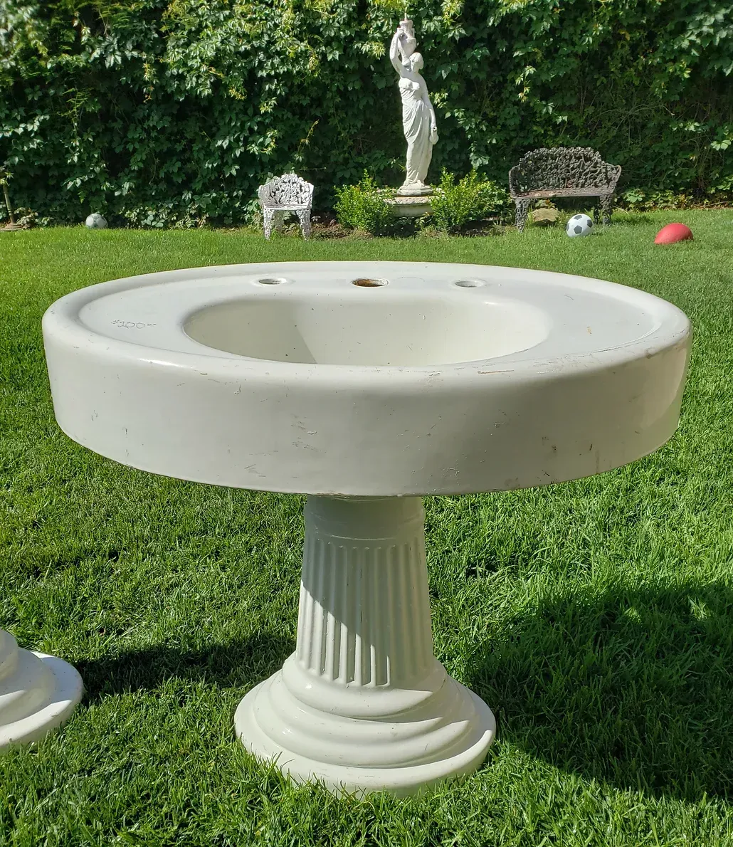 A white circular table in the grass with a statue in the background