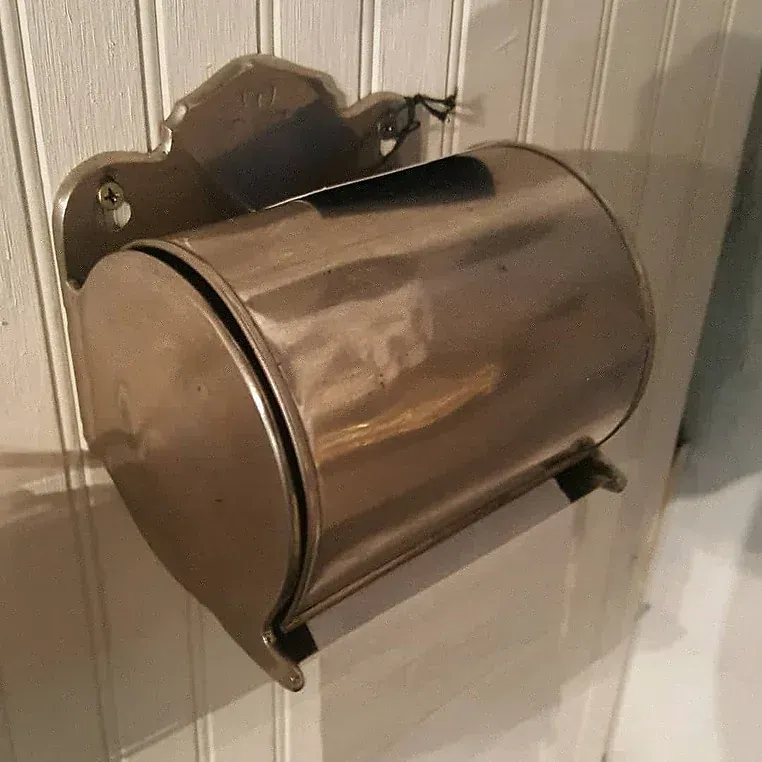 A stainless steel toilet paper dispenser is hanging on a wall.