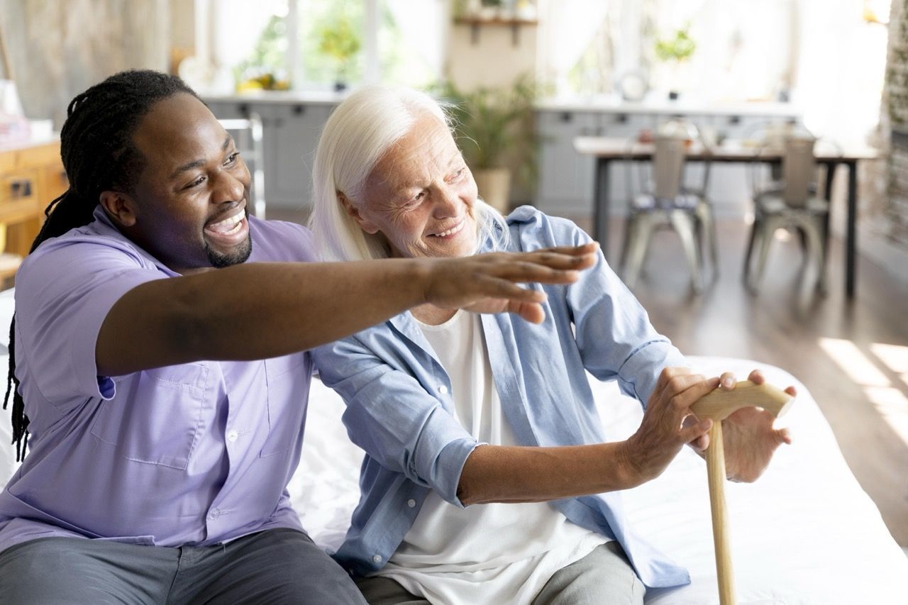 A man is helping an elderly woman with a cane.