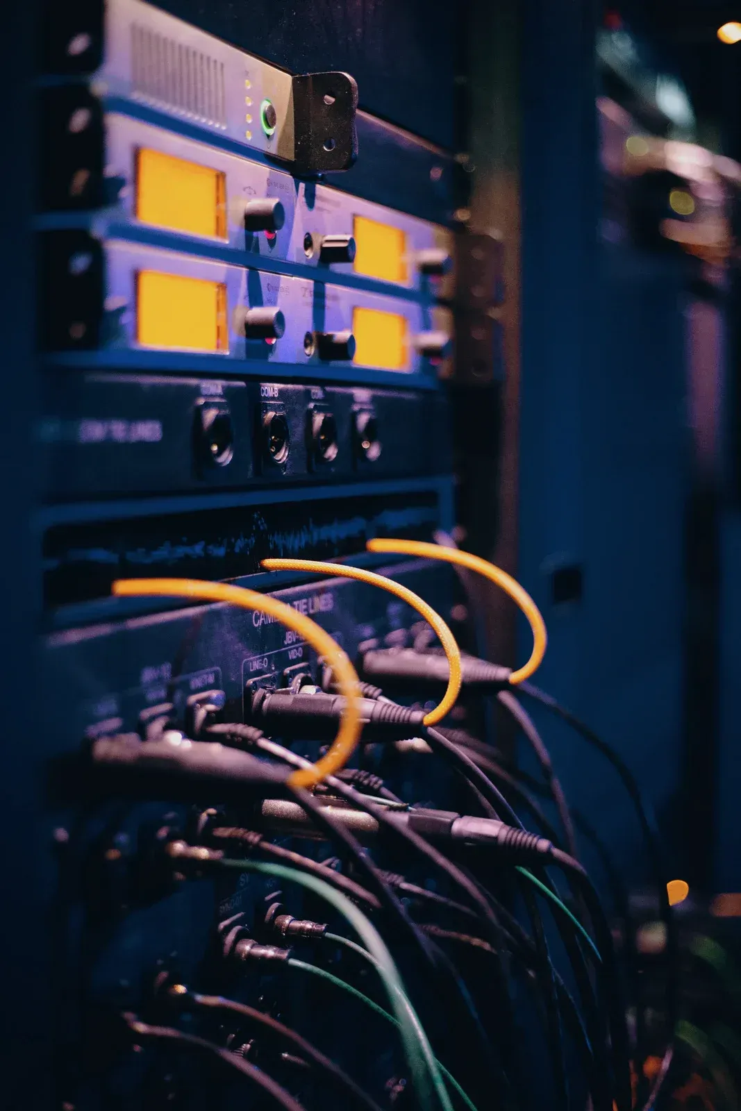 Audio equipment rack with black cables and yellow connectors.