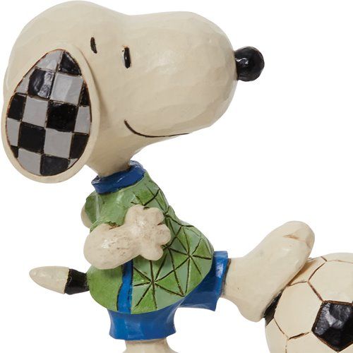 A figurine of snoopy kicking a soccer ball