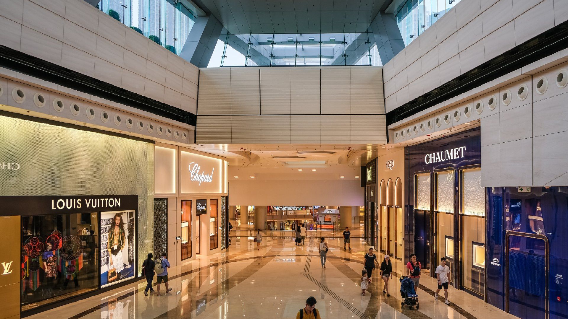 Stores A group of people are walking through a large shopping mall.