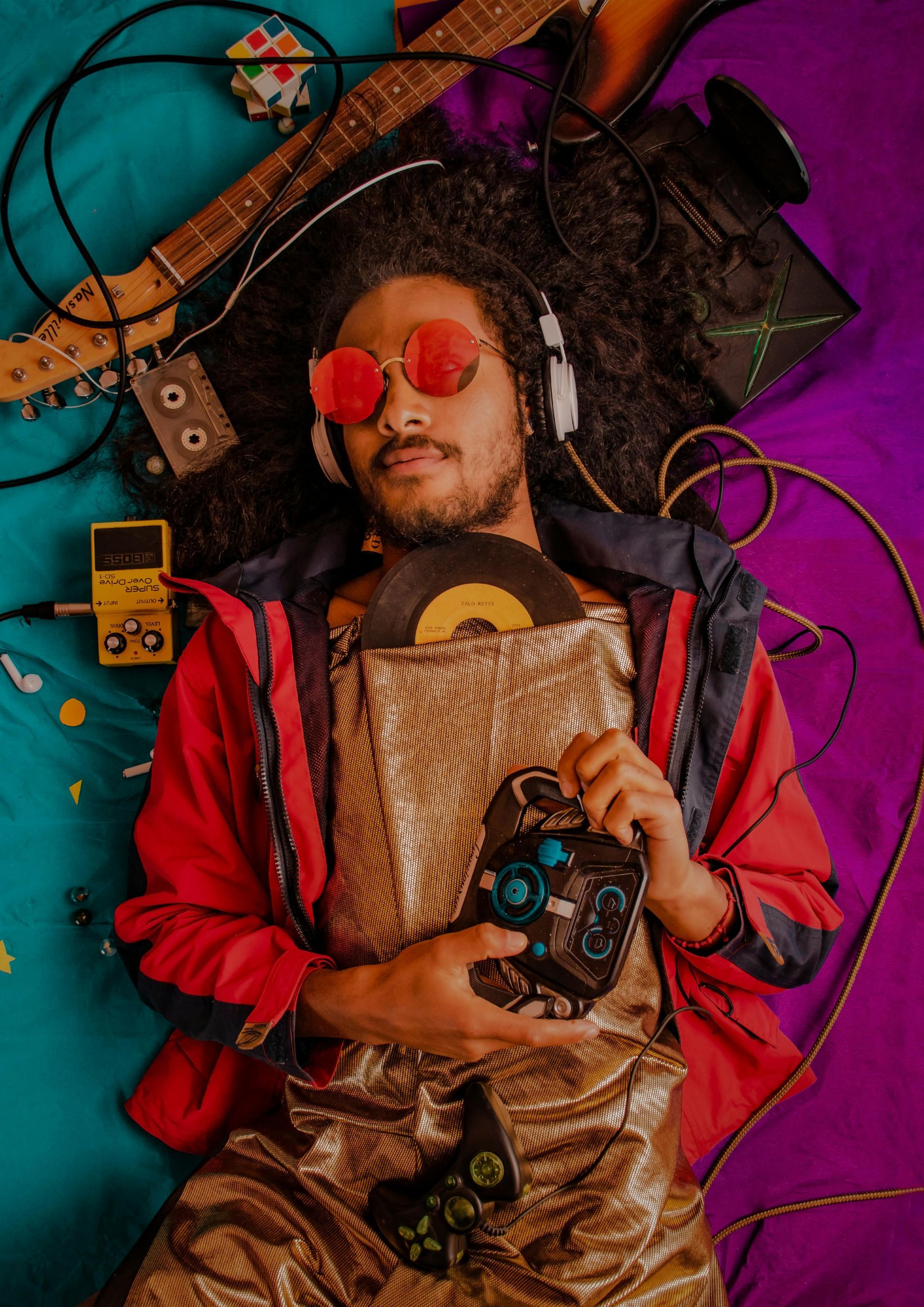 A man is laying on a bed holding a record and a video game controller.