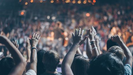Event Tickets A crowd of people are raising their hands in the air at a concert.