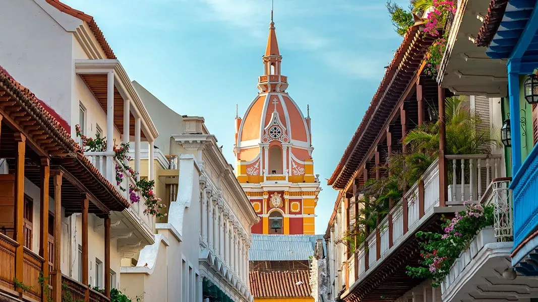 A narrow street with a clock tower in the middle of it.