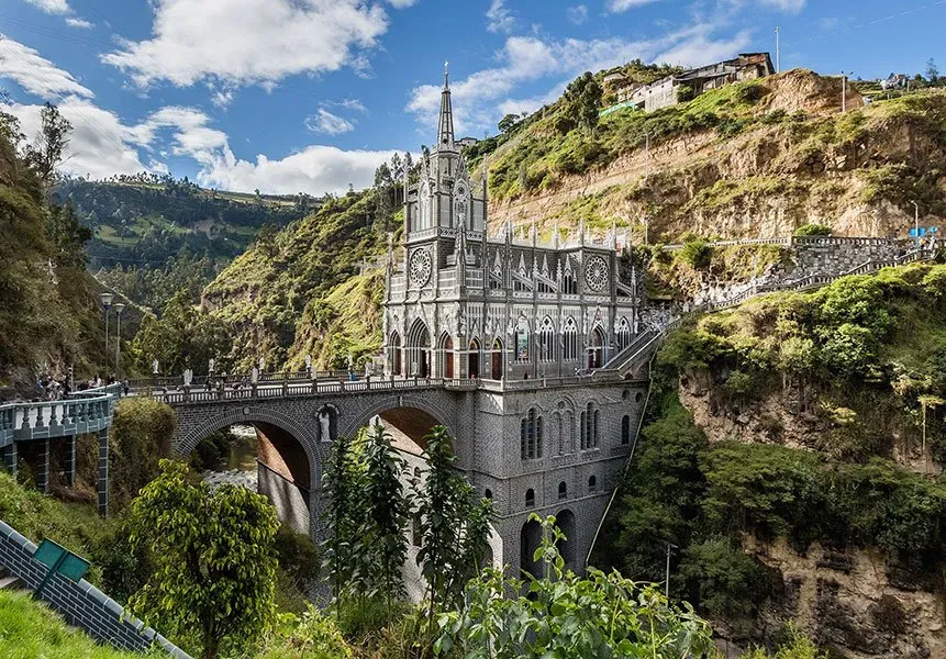 A large church is sitting on top of a hill next to a bridge.