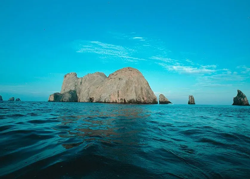 A large rock formation in the middle of the ocean.