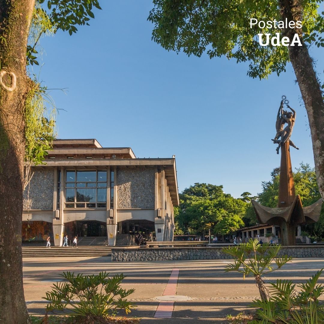 A large building with a statue in front of it that says postales udea