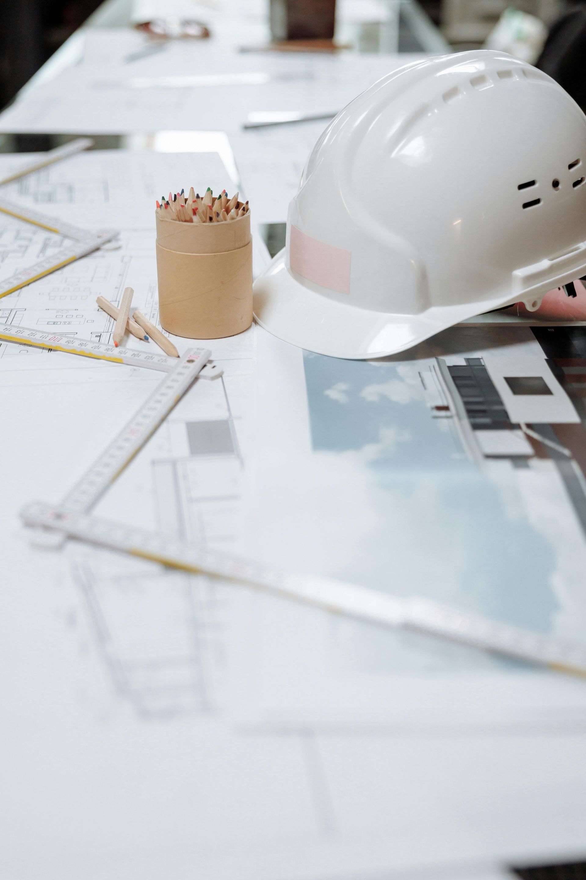 White hard hat and pencil on architectural blueprints at a construction desk