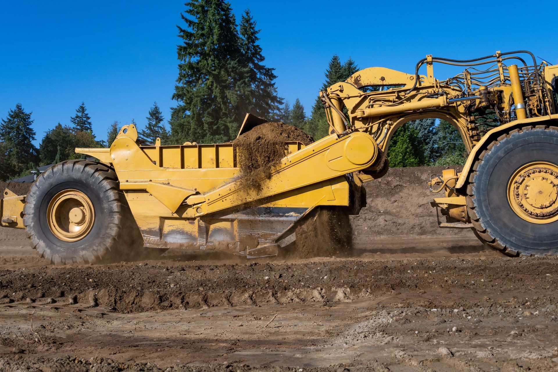 A yellow wheel tractor moves a pile of earth in a construction zone. A yellow wheel tractor moves a pile of earth in a construction zone.