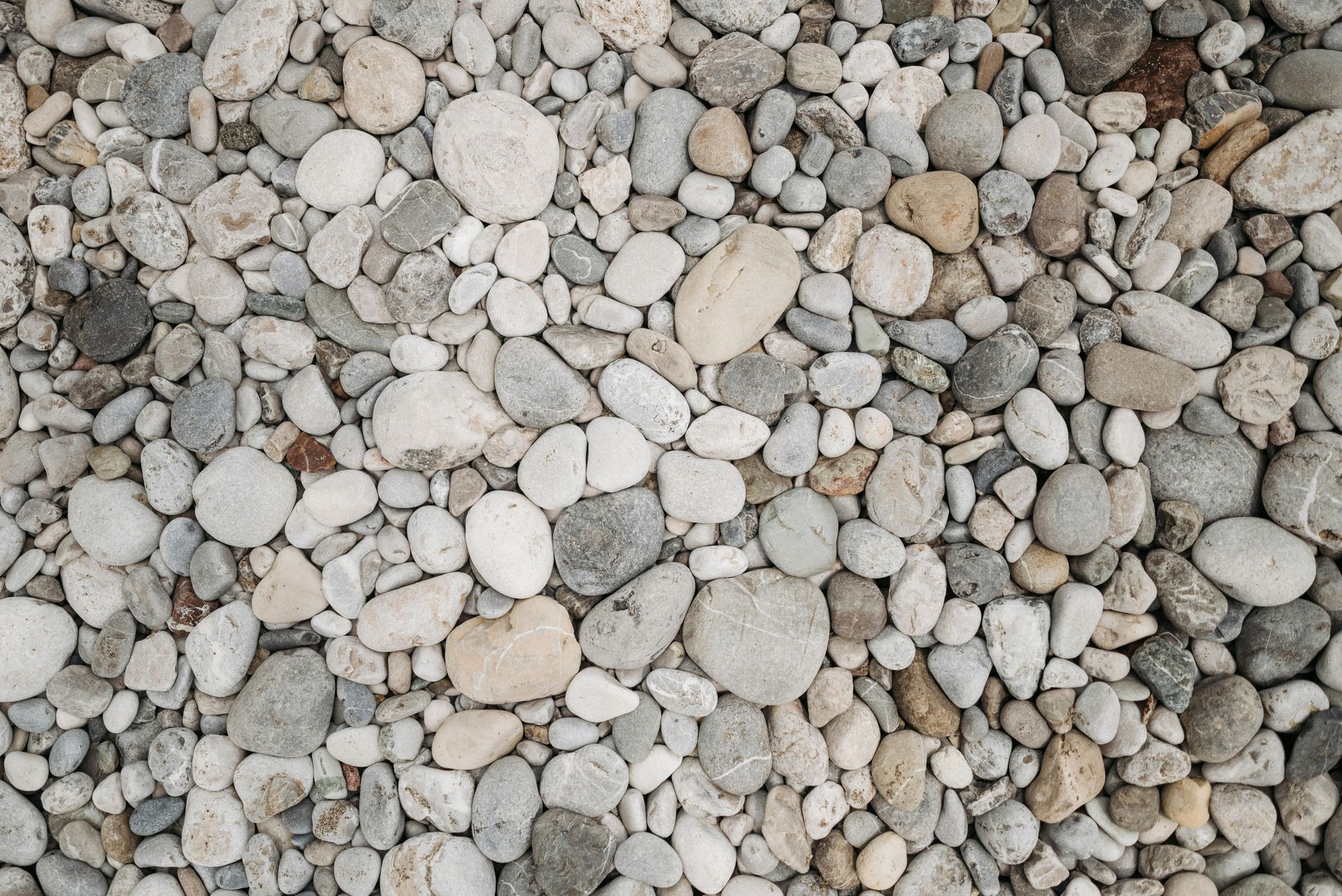Pile of smooth, rounded pebbles in shades of gray, beige, and white.