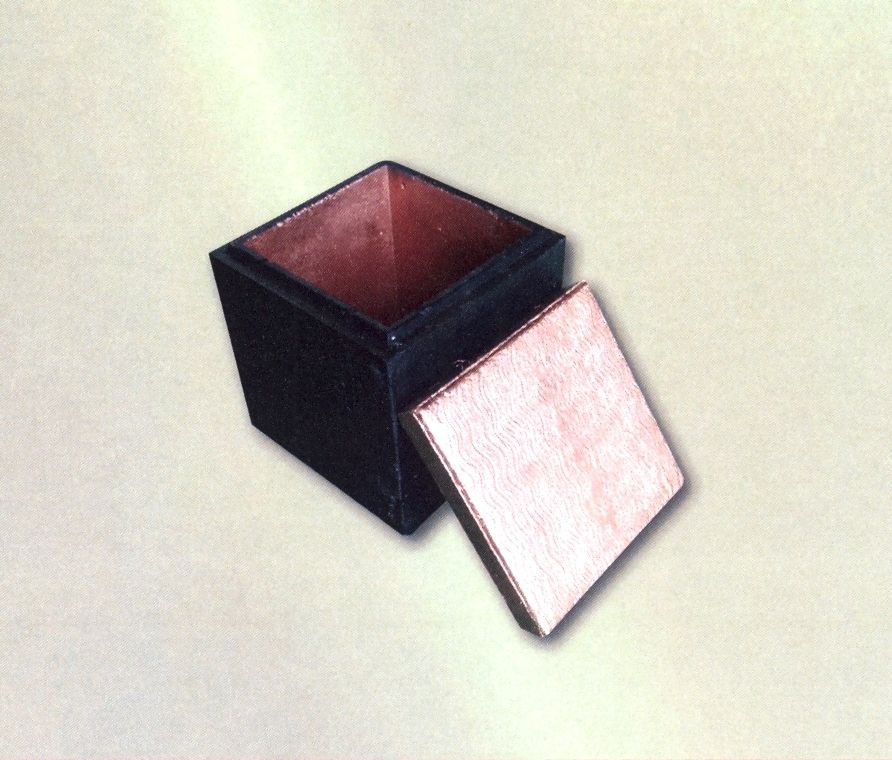Small black square box with a pink-lined interior and its lid leaning open beside it.