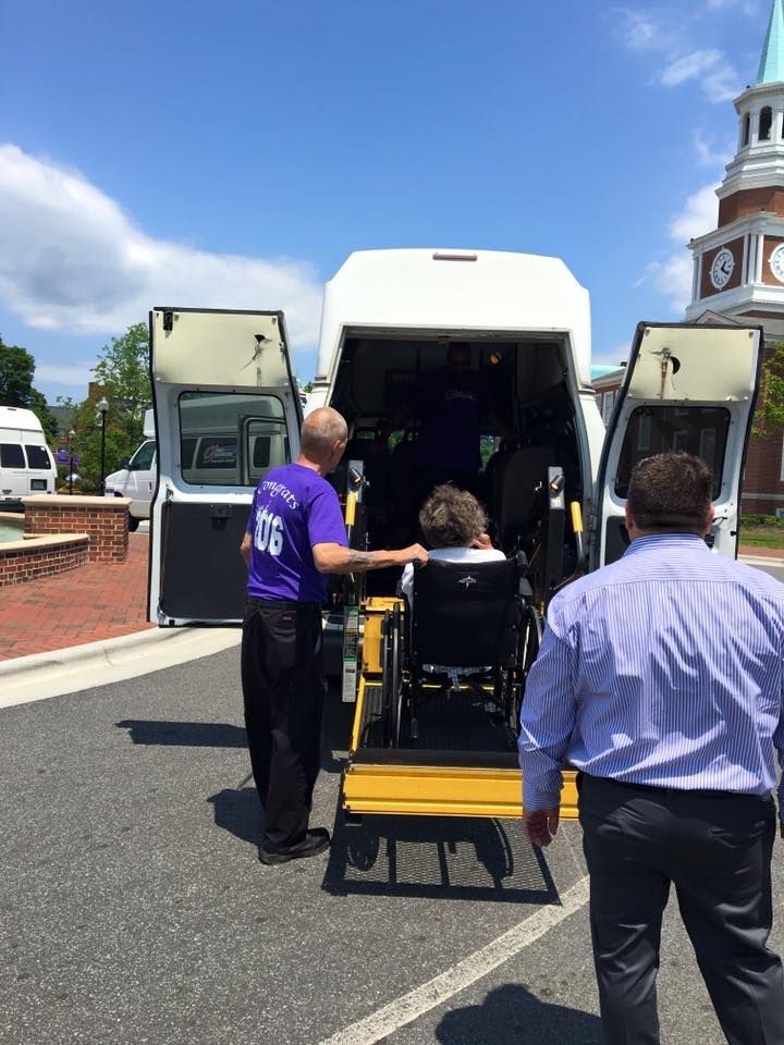 Person in wheelchair using lift on a white van.