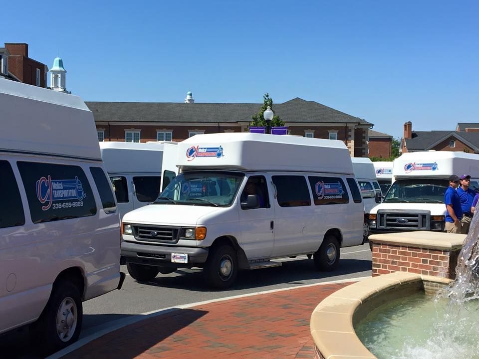 White transit vans parked, near brick fountain, buildings in background.