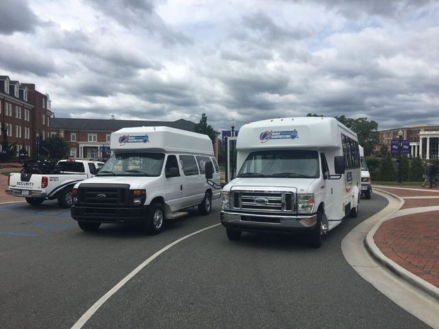 Two white shuttle buses driving on a road. Two white shuttle buses driving on a road.