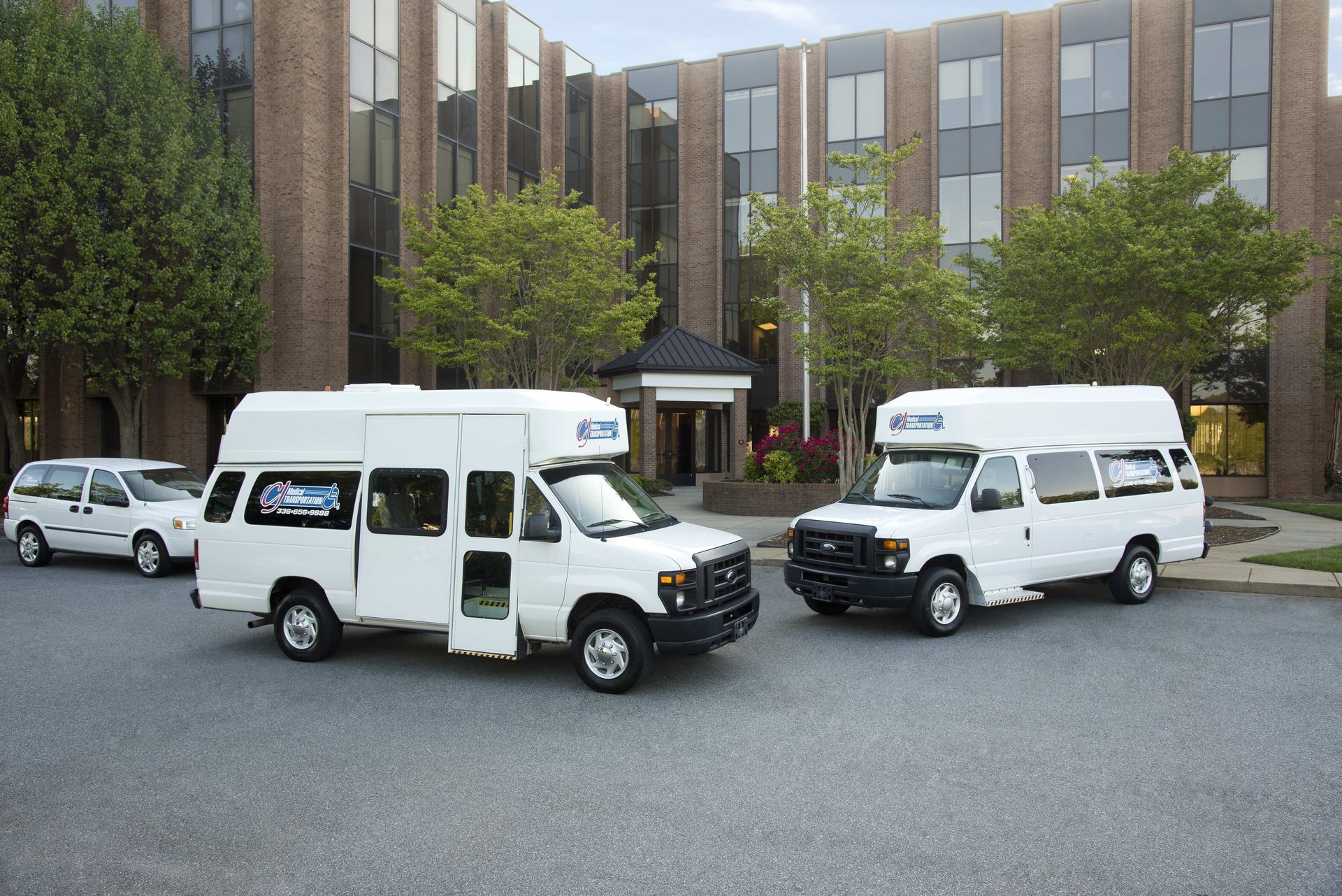 White accessible transit vans parked in front of a brick building.