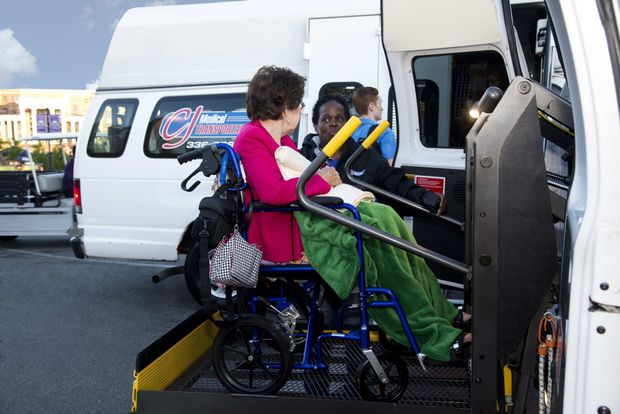 Woman in wheelchair assisted onto a lift of a white accessible van. Woman in wheelchair assisted onto a lift of a white accessible van.