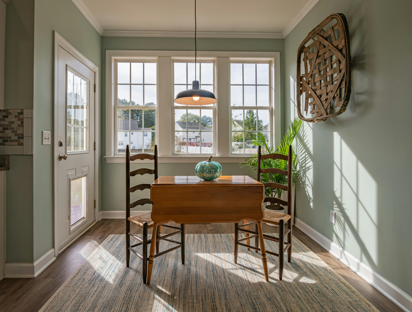 A dining room with a table and chairs in front of a window.