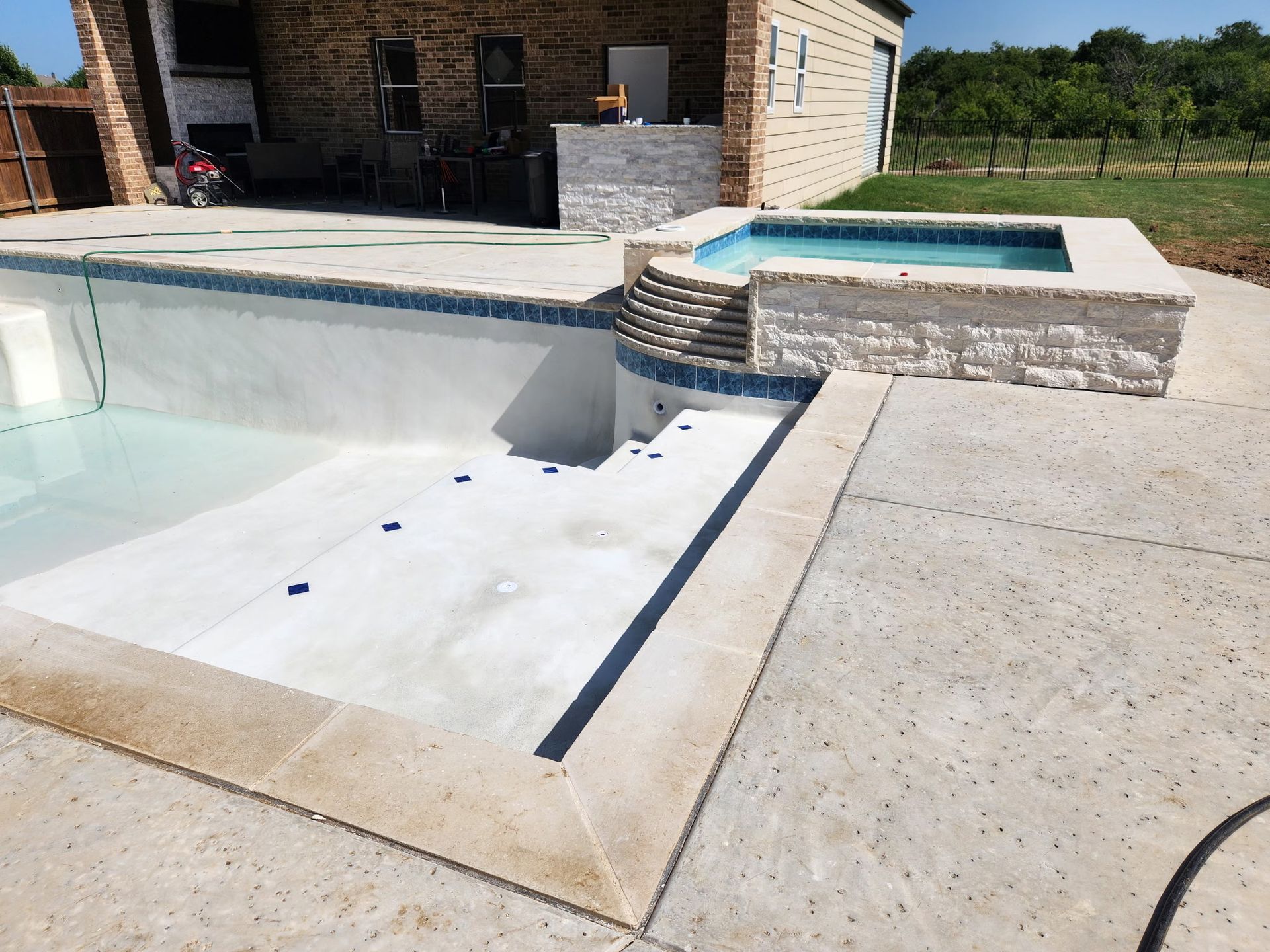 Backyard pool with a white disabled-access ramp and stone spa beside a patio